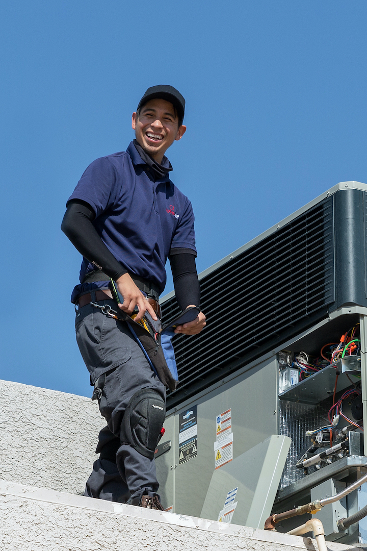 Alpha Air Technician having fun laughing while fixing an air conditioning unit.